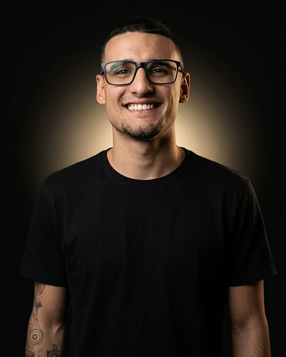 Pedro Menezes, web designer, sorrindo, de camiseta preta sobre fundo escuro